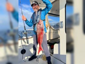 A proud angler displays his impressive catch aboard a boat, showcasing the thrill of fishing on the open water.
