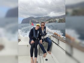 A happy couple enjoys their time on a boat, surrounded by stunning ocean views and the beautiful landscape of Madeira. Perfect for adventure seekers and romantic getaways.