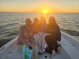 A joyful group of friends enjoys a beautiful sunset on a boat, creating unforgettable memories together on the water.