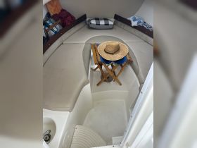 A cozy interior view of a boat cabin featuring seating, a straw hat, and a small table, perfect for relaxing during a day on the water.
