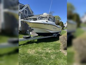 A well-maintained boat named 'After Hours' is docked on a trailer in a lush green yard, showcasing its sleek design against a clear blue sky.