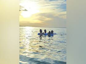 A group of friends enjoys a sunset swim while floating on colorful rafts, capturing the essence of a perfect beach day.
