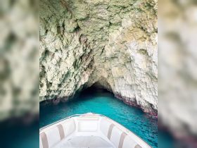 A stunning view from the bow of a boat entering a natural cave, surrounded by crystal-clear turquoise waters — perfect for exploring hidden gems on the water.