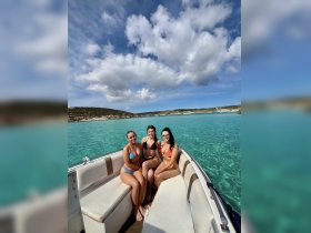 Three friends enjoy a sunny day on a boat, showcasing the stunning turquoise waters — perfect for summer adventures and memorable outings.