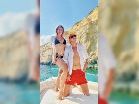 A couple poses on the deck of a boat, enjoying a sunny day on the water — perfect for romantic getaways or summer adventures.