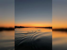 A stunning sunset reflects on the water, creating a picturesque scene perfect for evening boat rides and relaxation.