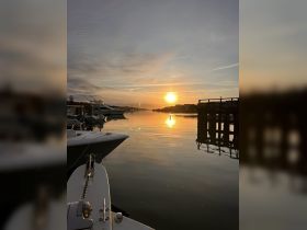 A serene sunset view from the dock, showcasing boats at rest and reflecting on calm waters — perfect for tranquil evening escapes.