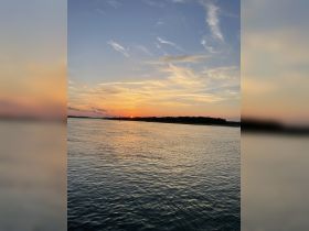 A stunning sunset over calm waters, capturing the serene beauty of the coastline — perfect for romantic evenings or peaceful boat rides.
