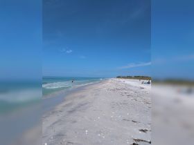 A serene beach scene with people enjoying the sun and surf, perfect for a relaxing day by the ocean.