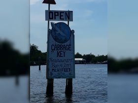 A sign indicating that Cabbage Key Restaurant, Bar & Inn is open, providing a welcoming message for visitors arriving by boat.