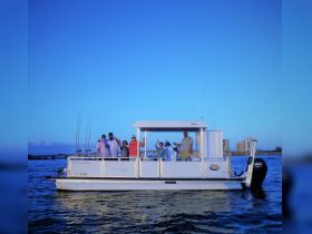 A cheerful group waves from a pontoon boat, enjoying a fun day on the water — perfect for fishing trips and family outings.