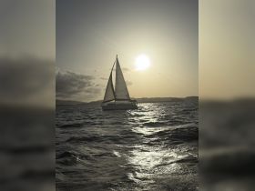 A stunning sailboat glides across the shimmering water at sunset, showcasing the beauty of sailing adventures.