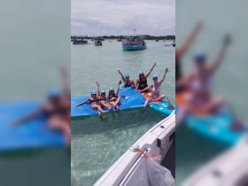 A lively group of friends enjoys a fun day on the water, relaxing on floating mats and soaking up the sun — perfect for summer gatherings and beach parties.