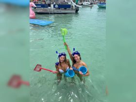 Two friends enjoy a fun snorkeling adventure in clear waters, equipped with nets and buckets, perfect for beach outings and aquatic exploration.