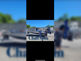Two individuals celebrate next to a newly acquired boat, showcasing excitement and camaraderie in a picturesque setting.