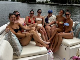 A lively group of friends enjoys a fun day on the boat, showcasing their vibrant bikinis and smiles, perfect for summer outings and celebrations on the water.
