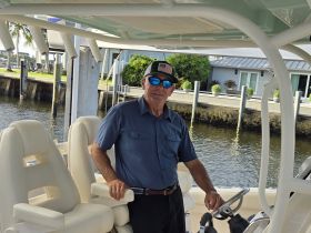 A man stands at the helm of a well-appointed boat, showcasing the comfortable seating and modern design — perfect for a day on the water.