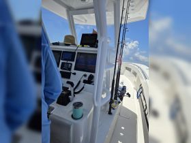 A view of the helm inside a fishing boat, showcasing the console and fishing gear, perfect for a day out on the water.