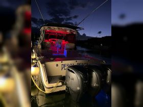 A striking view of a yacht's rear at dusk, illuminated with vibrant lights, showcasing its sleek design and powerful Yamaha engines.