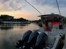 A sleek fishing boat is docked at sunset, showcasing its powerful engines and inviting interior lighting — perfect for evening excursions.
