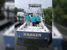 A group of three men stands proudly on the deck of the 'Kraken' boat at the dock, ready for a fishing adventure in Surfside Beach, SC.