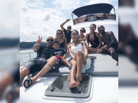A joyful group of friends and family relaxes on the deck of a yacht, enjoying a sunny day on the water — perfect for memorable outings and celebrations.