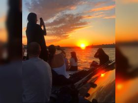 A group of friends captures the stunning sunset from their boat, creating a perfect backdrop for memorable moments on the water.