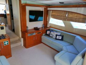 A cozy lounge area inside a boat featuring comfortable seating and a TV, perfect for relaxing during a day on the water.