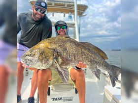 Two anglers proudly display their impressive catch aboard a fishing boat, showcasing the thrill of a successful day on the water.