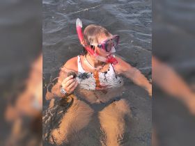 A young snorkeler holds a scallop while enjoying the underwater experience, showcasing the excitement of marine exploration.