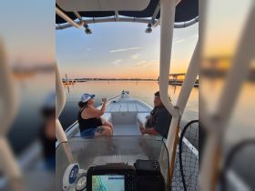 A couple enjoys drinks on a boat at sunset, creating a perfect backdrop for a relaxing evening on the water.
