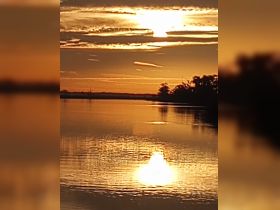 A serene sunset reflection on the water, capturing the tranquil beauty of nature. The image is slightly unclear, making details hard to discern.