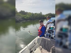 A young boy proudly displays his catch while fishing from a boat, showcasing a fun day on the water with family.