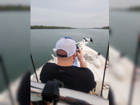 A person enjoys a peaceful moment on a boat, capturing the serene waterway scene while fishing. Ideal for showcasing outdoor adventures and fishing trips.