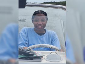 A young woman smiles while steering a boat, showcasing the joy of navigating the waters — perfect for adventure seekers and boating enthusiasts.