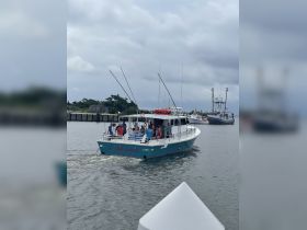 A lively group enjoys a fishing trip aboard the 'Jill Louise' as it departs from the dock, perfect for group adventures on the water.