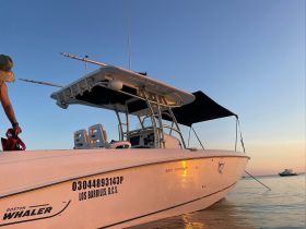 A stunning Boston Whaler 320 Outrage is docked at sunset, showcasing its sleek design and inviting atmosphere for a perfect day on the water.
