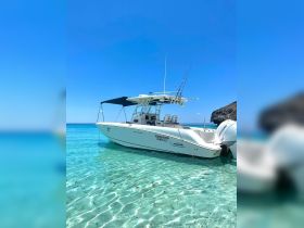 A sleek speedboat is docked in crystal-clear waters, showcasing its elegant design against a stunning blue sky — perfect for a day of adventure on the water.