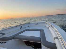 A serene view of the comfortable seating area inside a boat, perfect for relaxing while enjoying the sunset over the water.