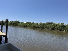 A view of a waterway with vegetation and structures in the background, but the focus and details are unclear.