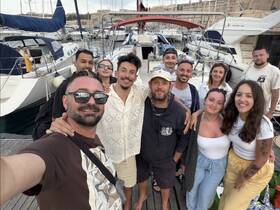 A cheerful group of friends poses for a selfie at the marina, surrounded by yachts — capturing the essence of friendship and adventure on the water.