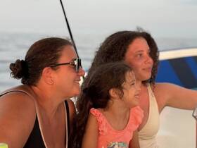 A joyful moment captured with a family enjoying their time on a boat, showcasing smiles and togetherness against a serene backdrop.