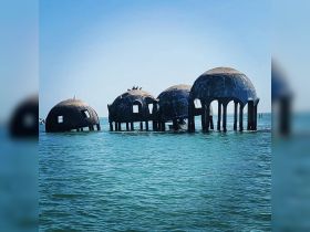 An intriguing view of partially submerged structures in the water, possibly remnants of a historical site, surrounded by clear blue waters.