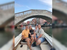 A cheerful group enjoys a scenic boat ride through the picturesque canals of Venice, capturing the essence of sightseeing in this iconic city.