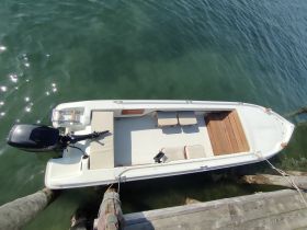 Aerial view of a sleek speedboat docked, showcasing its clean lines and spacious seating area, perfect for a day on the water.