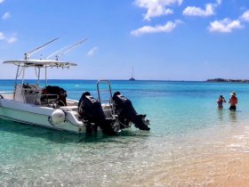 Two guests enjoy snorkeling in the clear waters near a boat, capturing the essence of a perfect beach day filled with adventure and relaxation.