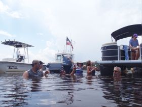 A lively group enjoys a fun day in the water near their pontoon boats, creating unforgettable memories while swimming and socializing.