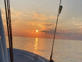 A serene sunset view from the deck of a boat, showcasing the tranquil ocean and vibrant colors of the sky — perfect for peaceful evening cruises.