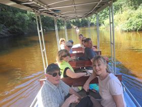 A cheerful group enjoys a scenic boat ride along a tranquil river, perfect for exploring nature and creating memorable experiences.