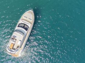 A stunning aerial view of a sleek yacht cruising through vibrant turquoise waters, showcasing its elegant design and luxurious features.